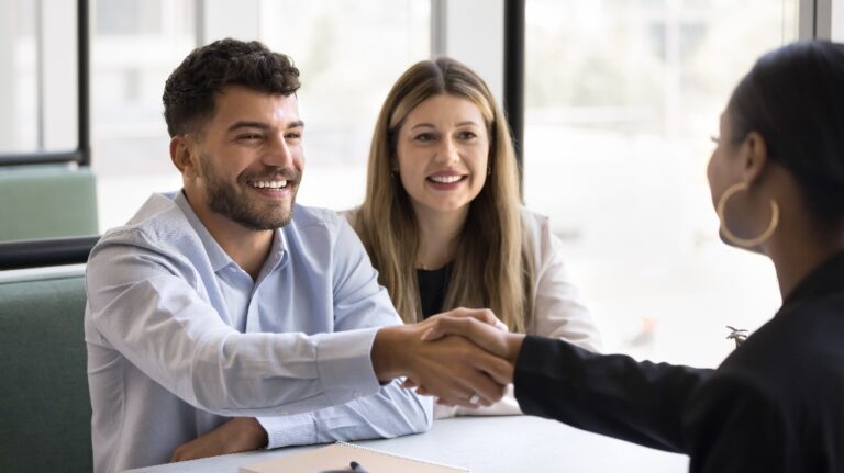 Cheerful young couple shaking hands with lawyer