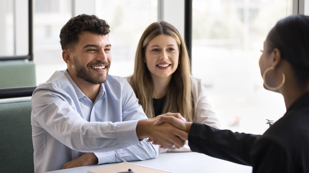 Cheerful young couple shaking hands with lawyer
